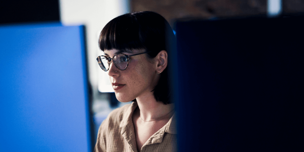Une jeune femme brune concentrée devant un ordinateur